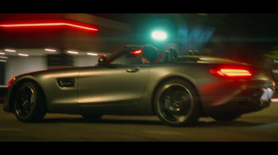 a silver car driving down a street at night