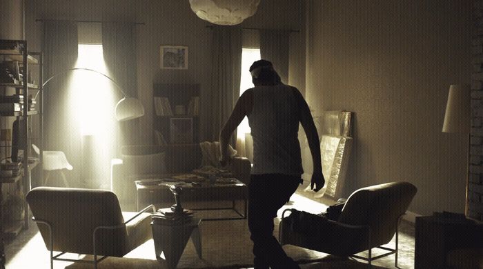 a man standing in a living room next to a chair