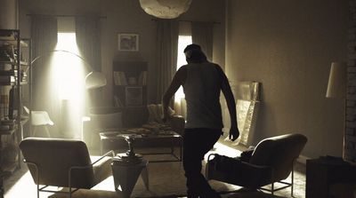 a man standing in a living room next to a chair