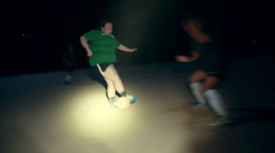 a man in a green shirt kicking a soccer ball