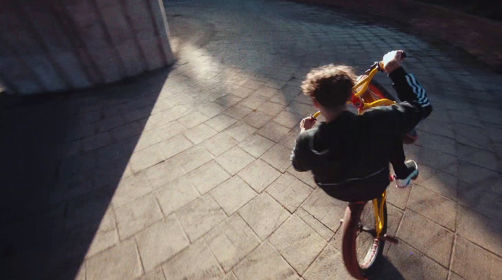 a little boy riding a bike down a sidewalk