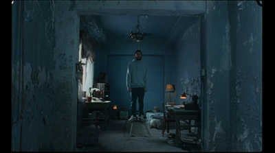 a man standing in a dark room next to a lamp