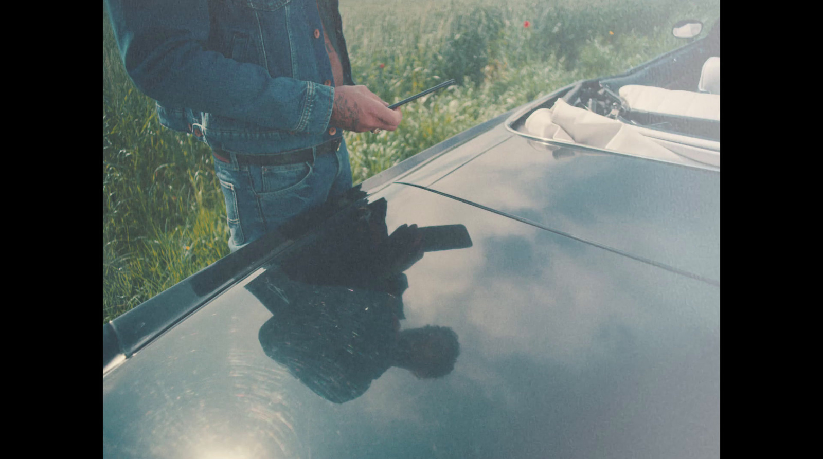 a man standing next to a car holding a cell phone