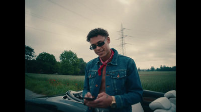 a man wearing sunglasses and a tie standing next to a car