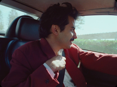 a man sitting in a car with a tie around his neck