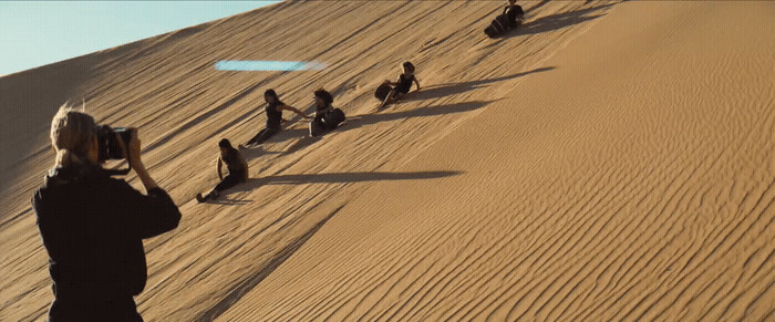 a woman taking a picture of a group of people in the desert