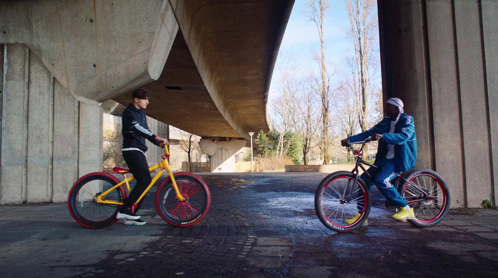 a couple of people riding bikes under a bridge