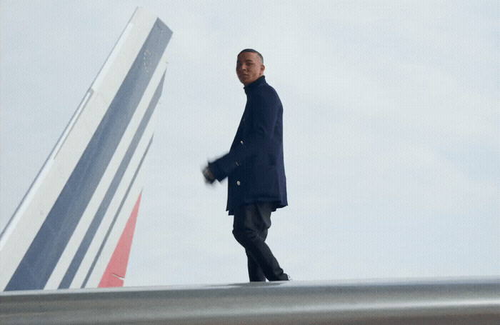 a man in a black coat is walking towards a plane