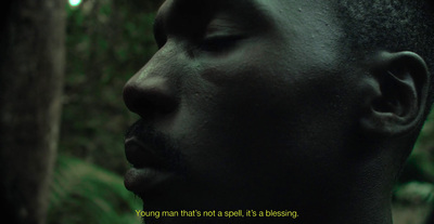 a man with his eyes closed standing in a forest