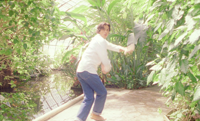 a man in a white shirt is skateboarding in a greenhouse