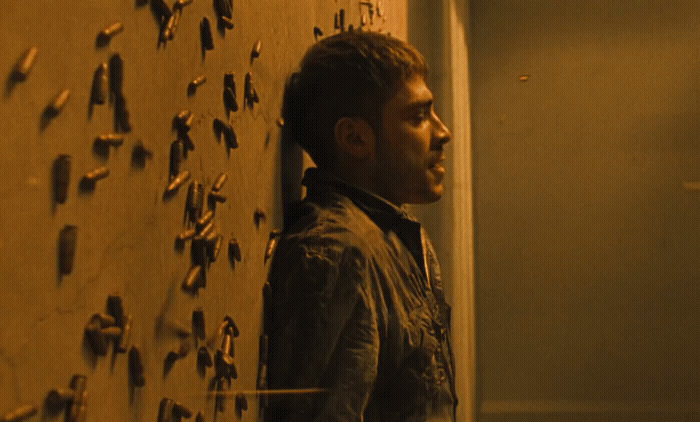 a man standing next to a wall covered in bullet holes