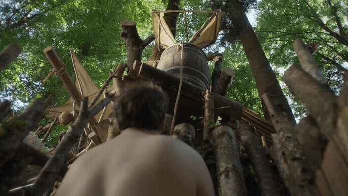 a man standing next to a pile of logs