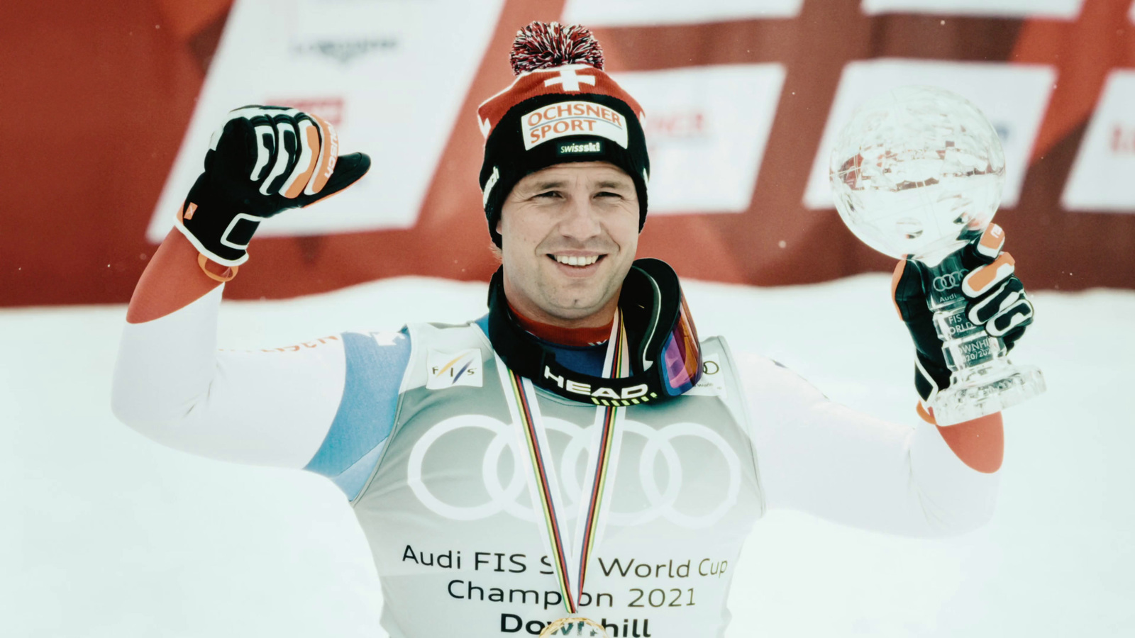 a man in a ski suit holding up a trophy