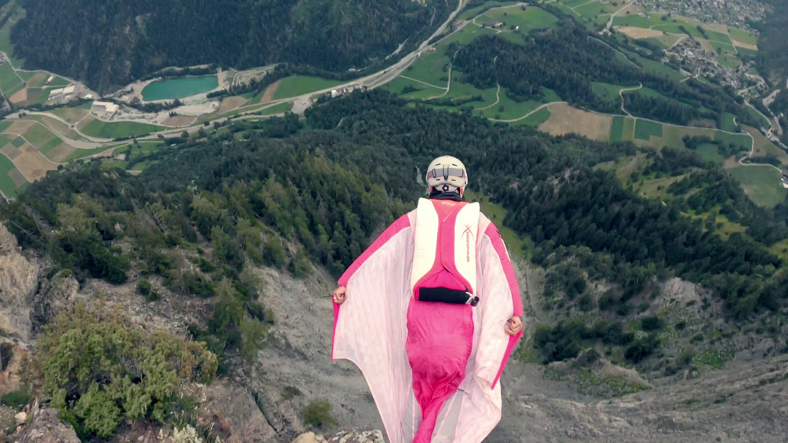 a woman in a pink dress standing on top of a mountain