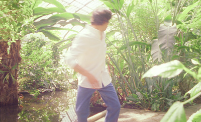 a man in a white shirt and blue pants walking through a jungle