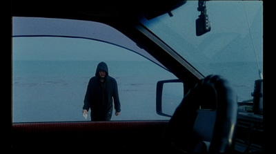 a man in a black hoodie is looking out of a car window