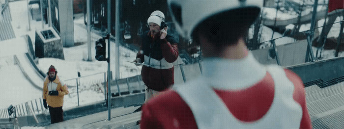 a man in a red and white jacket talking on a cell phone