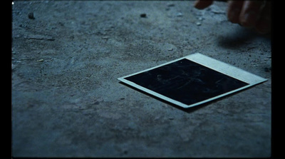 a square picture laying on the ground with a hand reaching for it