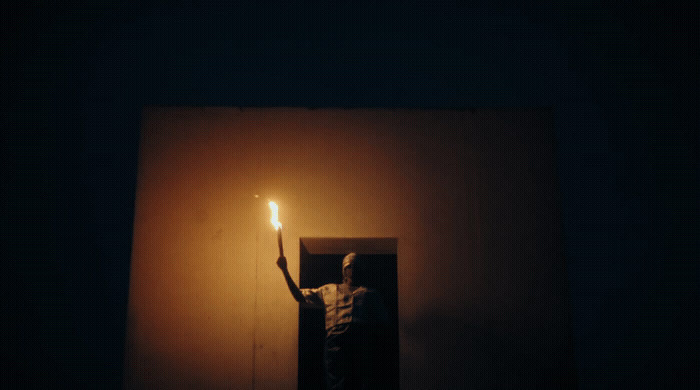 a person holding a lit candle in the dark