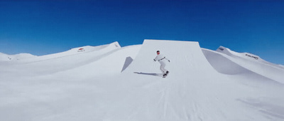 a man riding a snowboard down the side of a snow covered slope