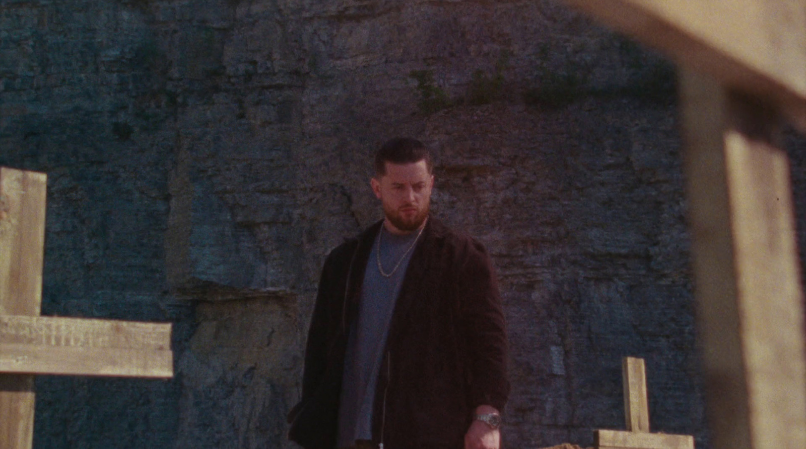 a man standing in front of a stone wall