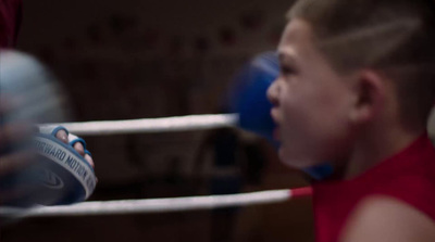 a young boy in a red shirt is in a boxing ring