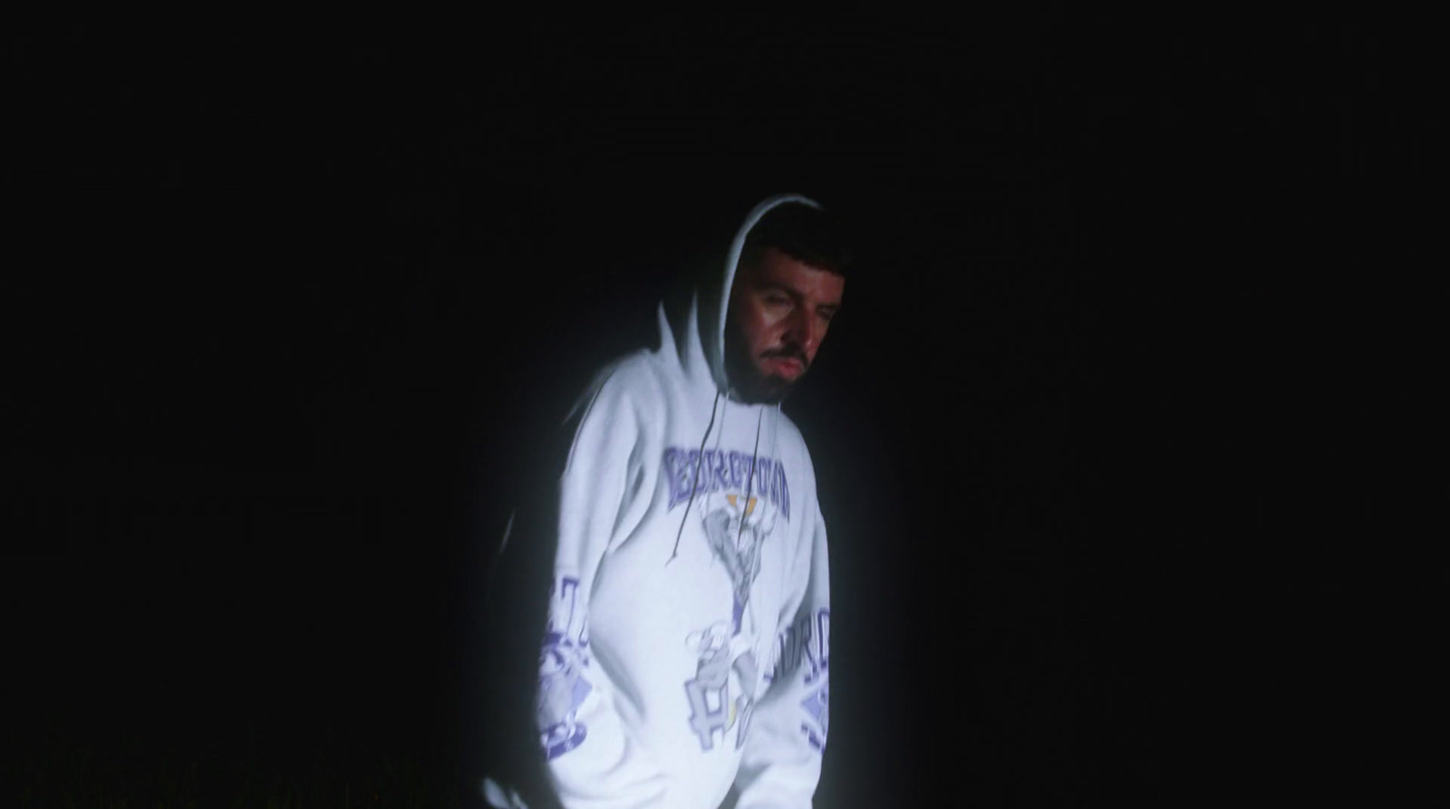 a man in a hoodie standing in the dark