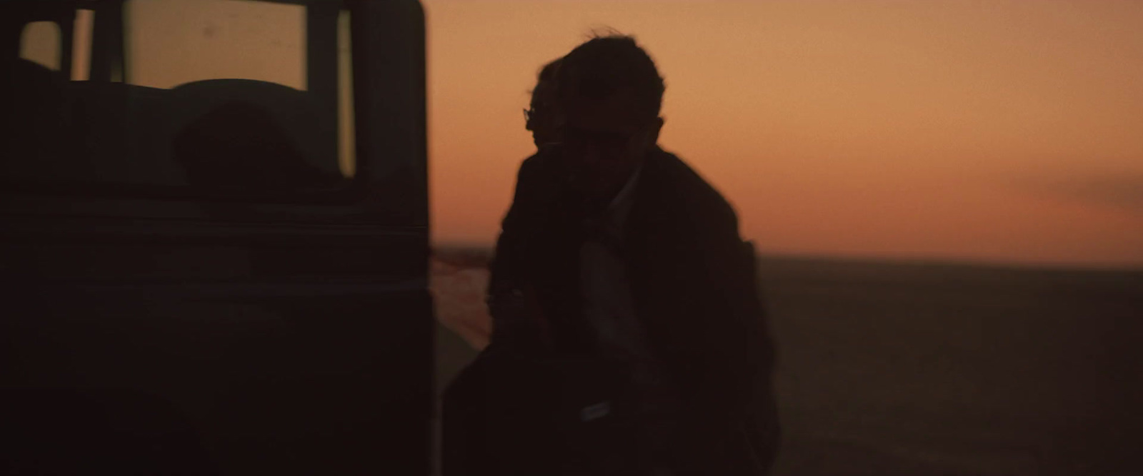 a man standing in front of a bus at sunset