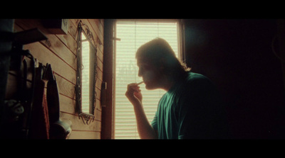 a man standing in front of a window with a toothbrush in his mouth