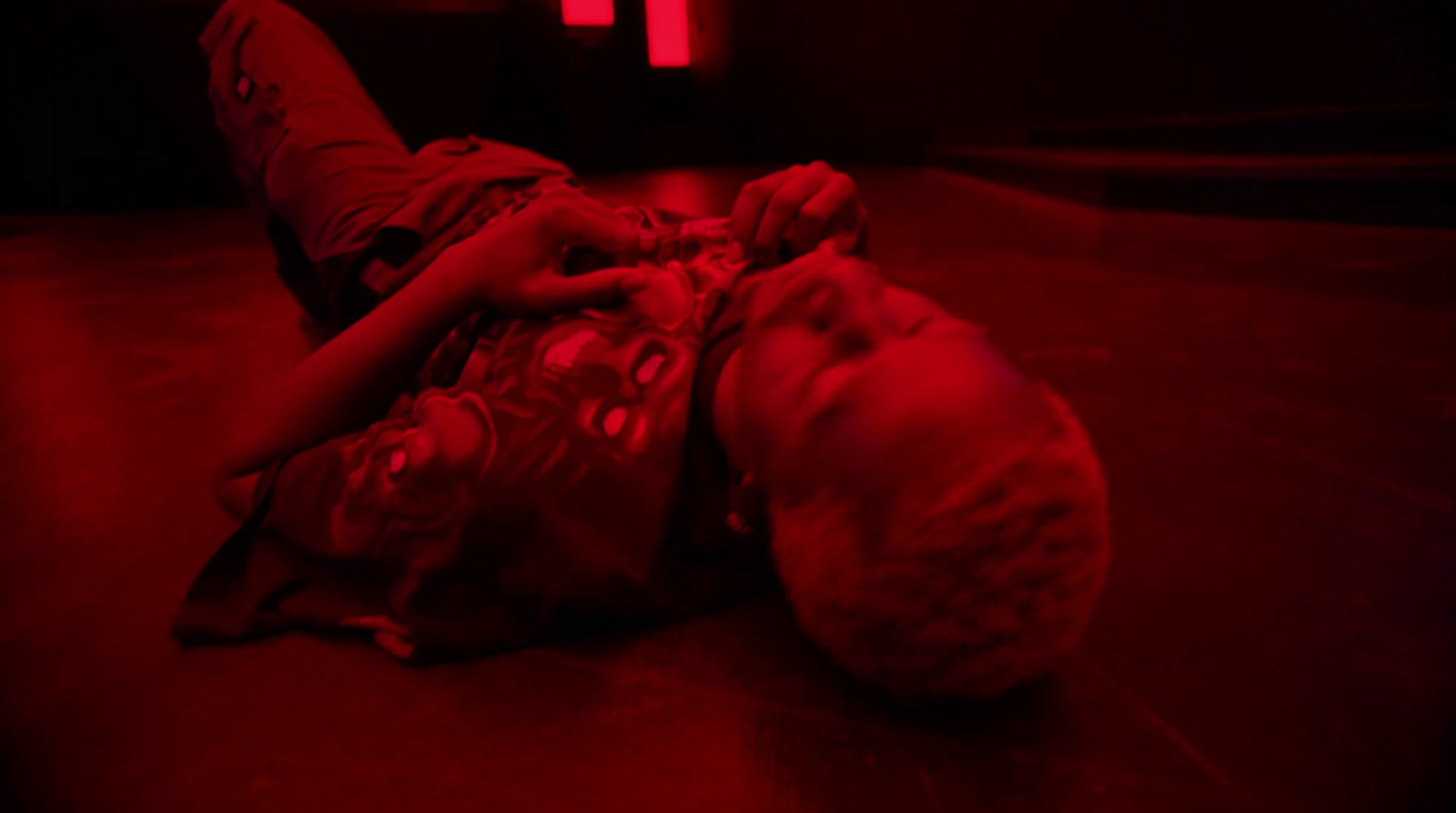 a young boy laying on the floor in a dark room