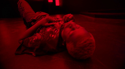 a young boy laying on the floor in a dark room