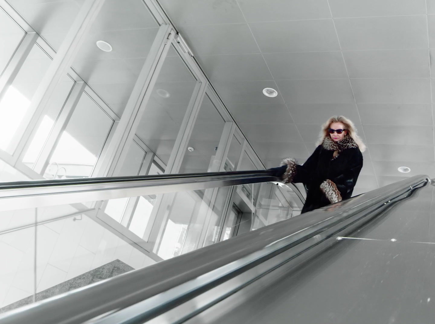 a woman riding an escalator down a metal handrail