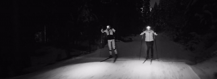 a couple of people riding skis down a snow covered slope