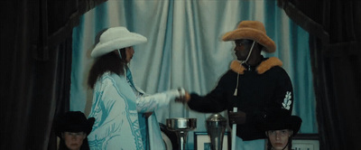 a man in a white hat shaking hands with a woman in a blue dress