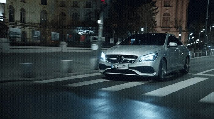 a silver car driving down a street at night