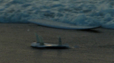 a small toy airplane sitting on top of a sandy beach