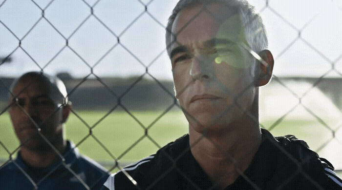 a man standing behind a chain link fence