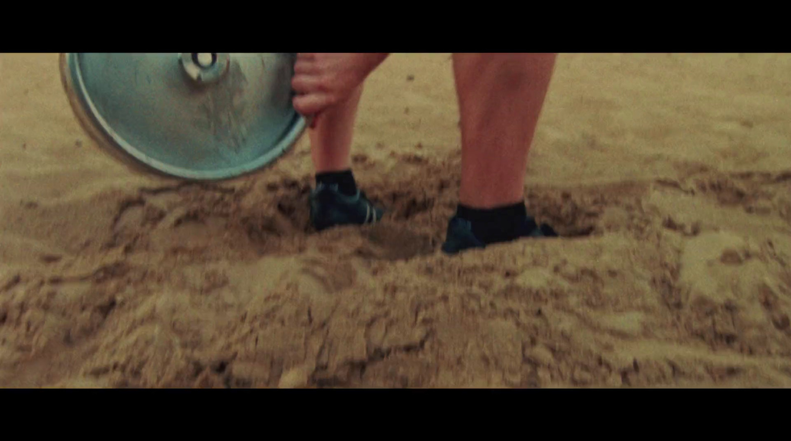 a person standing in the sand with a disc