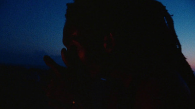 a man with dreadlocks standing in the dark