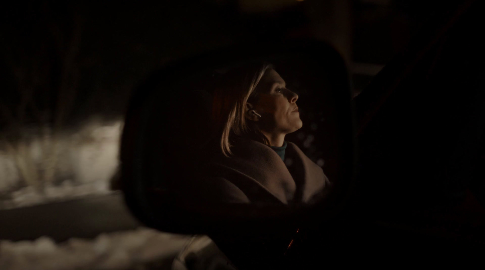 a woman looking out of a car window at night