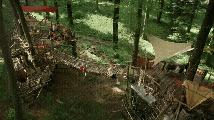 a group of people on a rope bridge in the woods