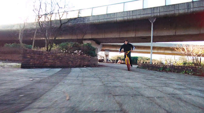 a man riding a skateboard down a street under a bridge