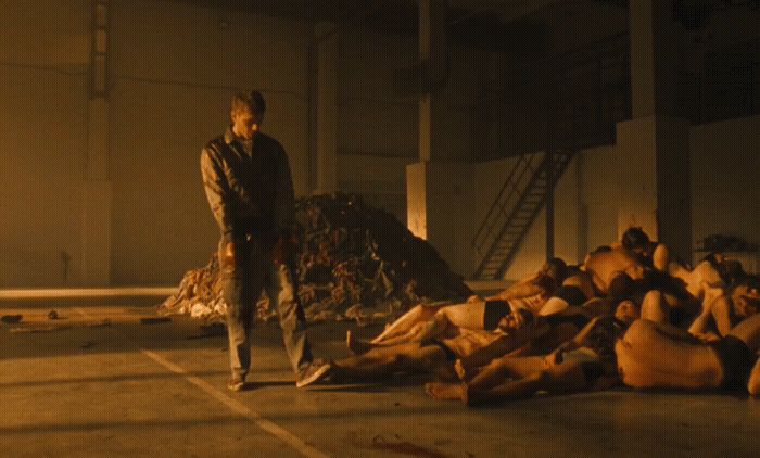 a man standing next to a pile of dead bodies