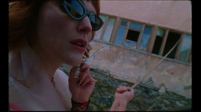 a woman in sunglasses smoking a cigarette in front of a building