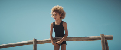 a young girl standing on a wooden fence