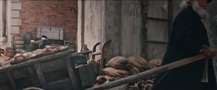 a man pushing a wheelbarrow full of wood