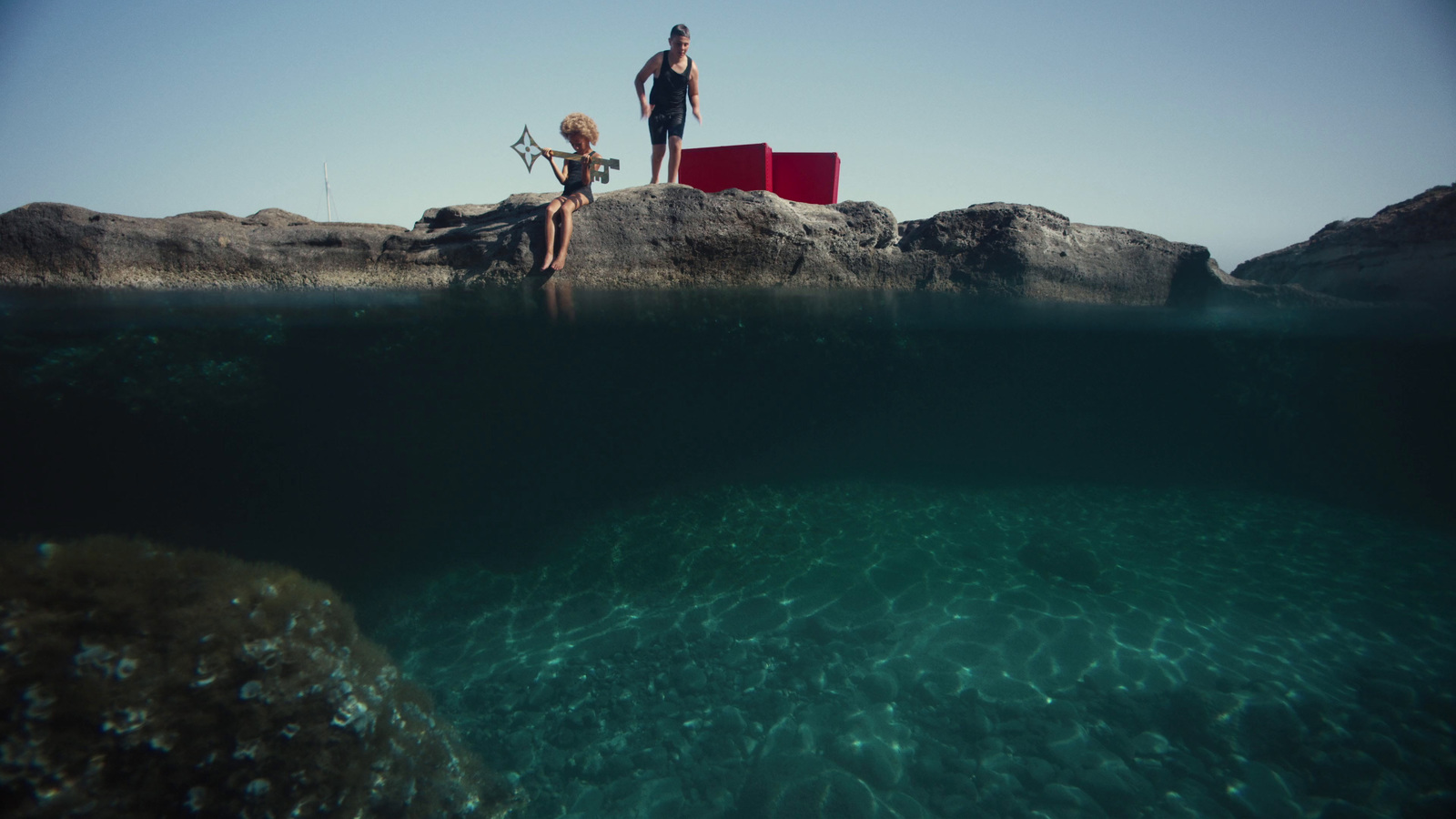 a couple of people standing on top of a rock next to a body of water