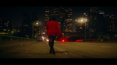 a woman in a red jacket walking across a street