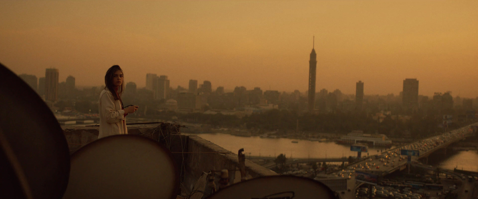 a woman standing on top of a building next to a river