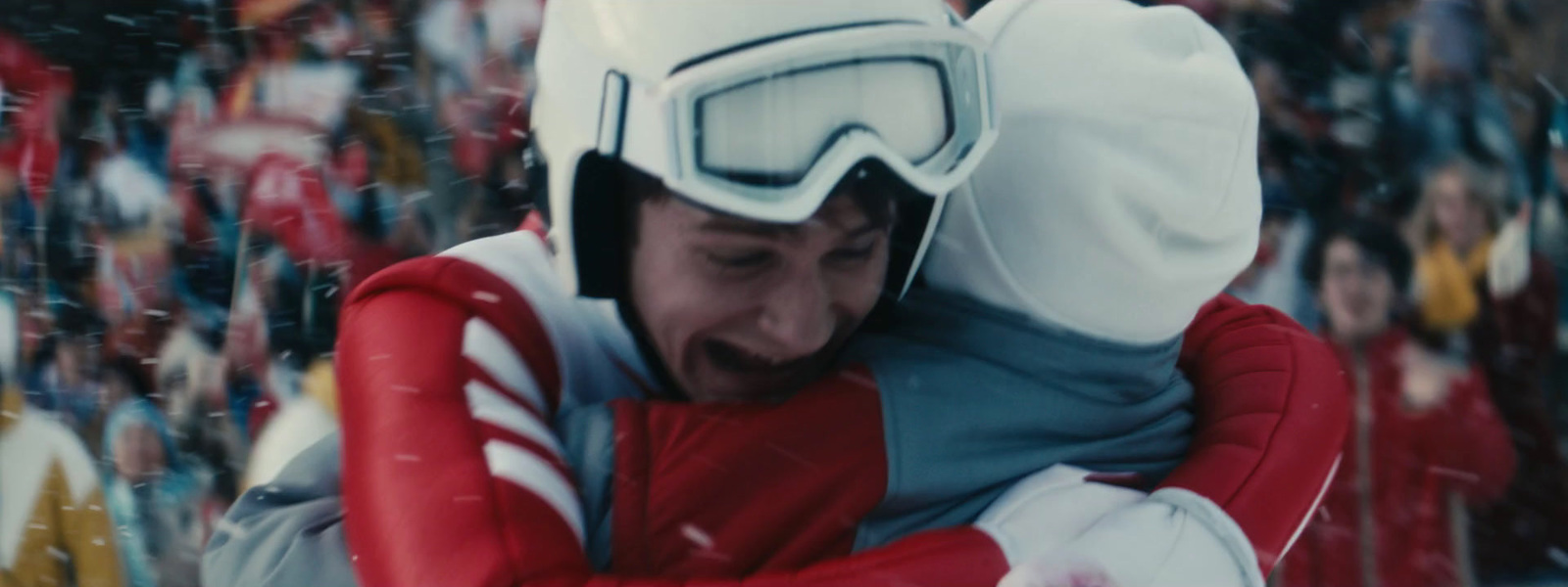 a man in a red and white ski suit hugging another man in a red and